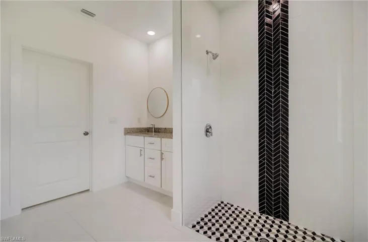 Bathroom featuring tile flooring, tiled shower, and vanity