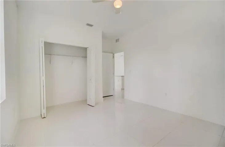 Unfurnished bedroom featuring a closet, ceiling fan, and light tile floors