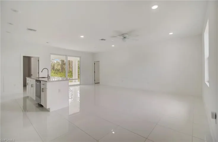 Kitchen with stainless steel dishwasher, an island with sink, light tile flooring, sink, and white cabinetry