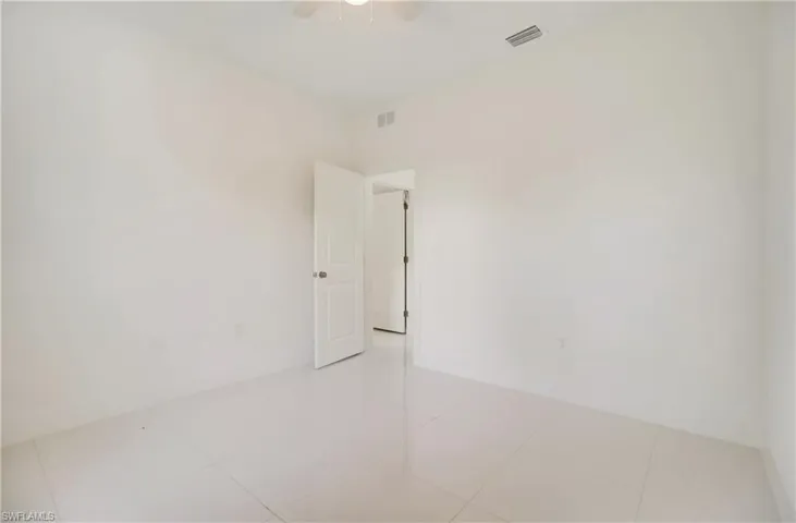 Unfurnished room with ceiling fan and light tile flooring