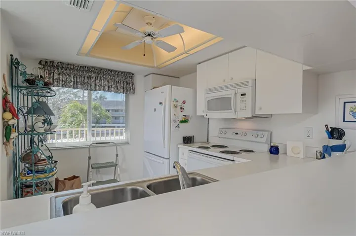 Kitchen featuring white cabinets, white appliances, and ceiling fan