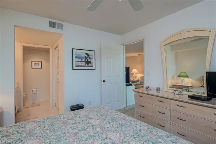 Bedroom featuring ceiling fan, a closet, connected bathroom, and light tile patterned floors