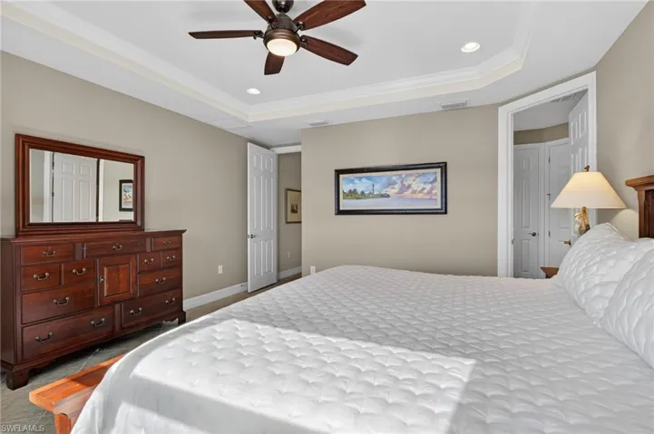 Bedroom featuring recessed lighting, ornamental molding, a ceiling fan, a tray ceiling, and light colored carpet