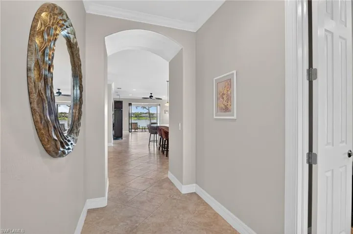 Corridor featuring arched walkways, and rounded edges, light tile patterned floors, and ornamental molding