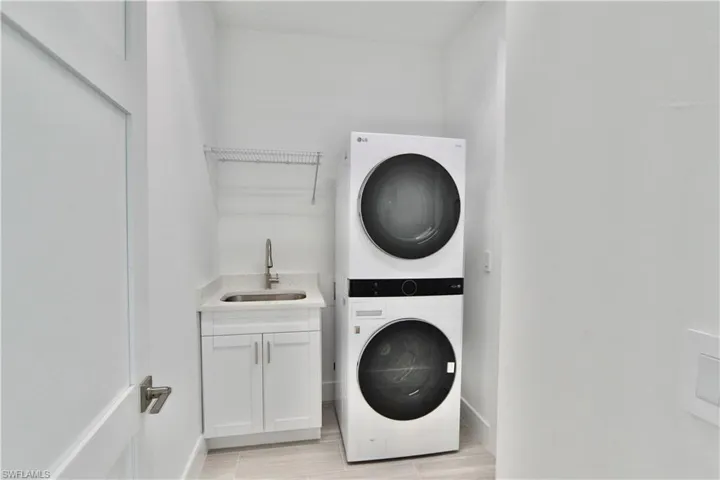 Laundry room featuring sink, stacked washer and clothes dryer