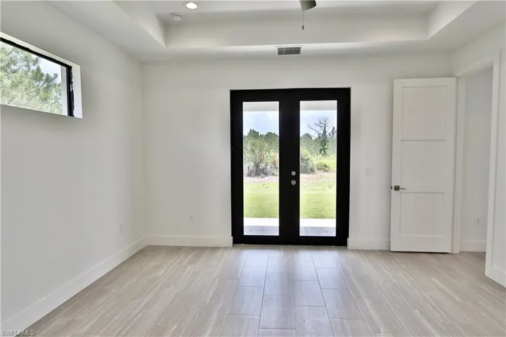 Main Bedroom with a raised ceiling, a healthy amount of sunlight, and french doors