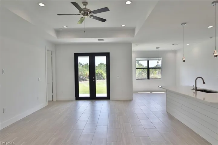 Living room with a tray ceiling, french doors and ceiling fan