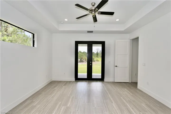 Main bedroom with a raised ceiling, a healthy amount of sunlight, and french doors