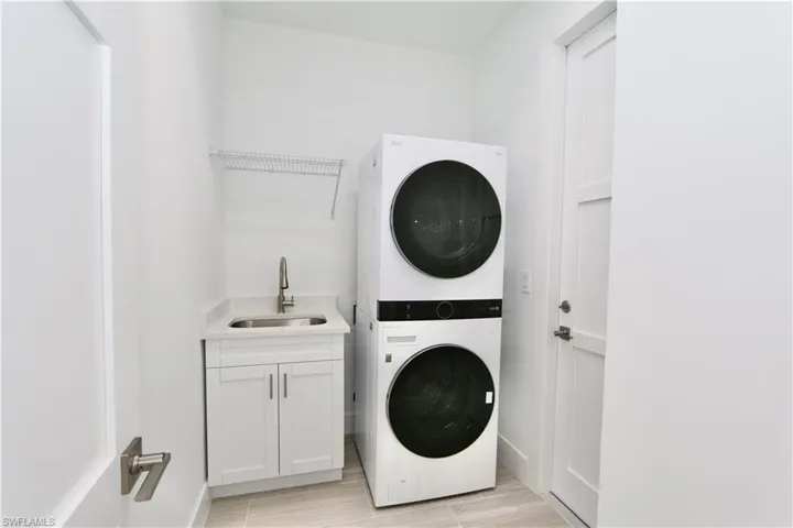 Laundry room with sink, stacked washer / dryer