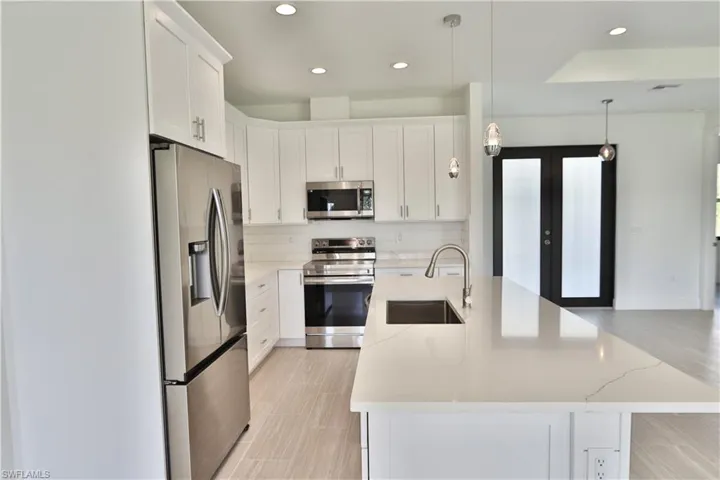 Kitchen with white cabinets, sink, tasteful backsplash, and stainless steel appliances