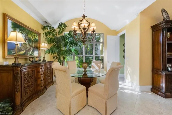 Dining space with a chandelier, vaulted ceiling, light tile patterned floors, and ornamental molding