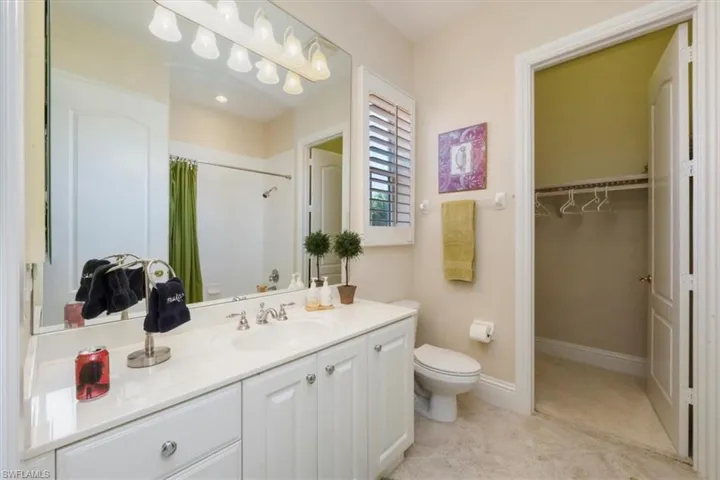 Bathroom with curtained shower, vanity, a spacious closet, and light tile patterned floors