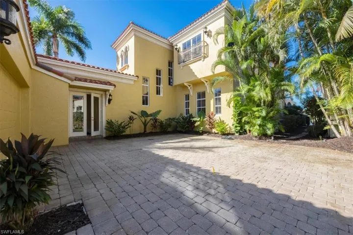 Rear view of property featuring a patio, stucco siding, and a tiled roof