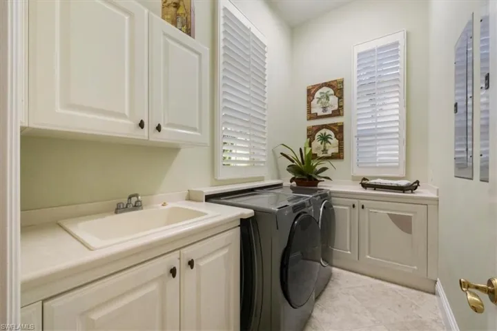 Laundry area featuring separate washer and dryer, cabinet space, and light tile patterned flooring