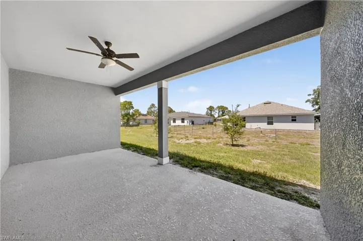 The property features a covered patio with a ceiling fan, overlooking a spacious backyard area