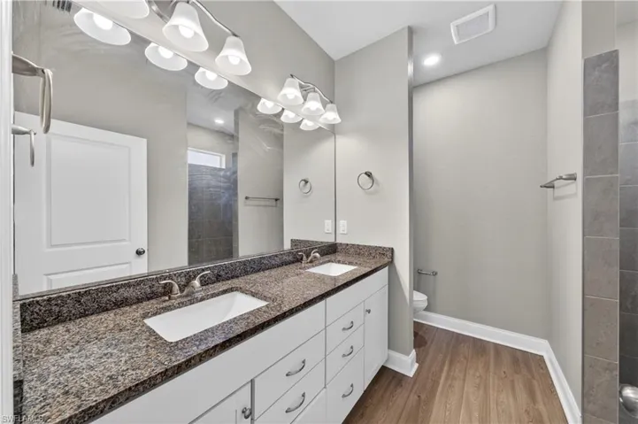 The bathroom features a dual vanity with a granite countertop, undermount sinks, and ample storage cabinetry