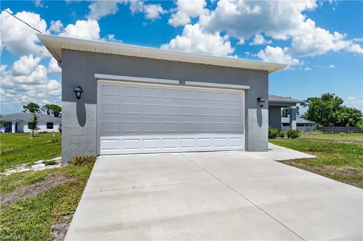 The property features a concrete driveway leading to a white paneled garage door