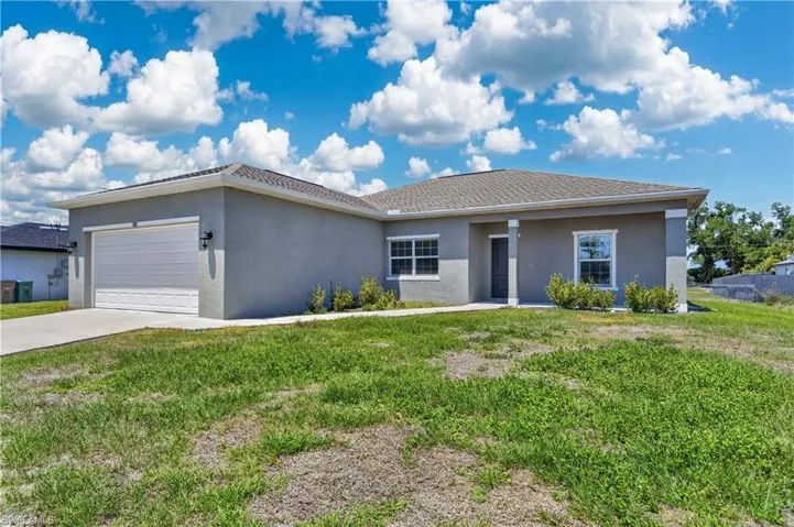 The property features a stucco exterior, a paved driveway, and a two-car garage