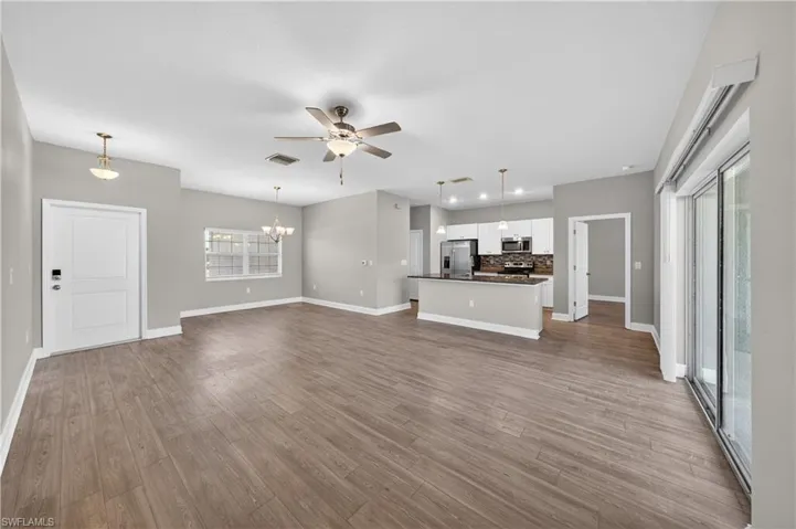 Spacious open concept living area featuring wood-look flooring, light gray walls, a ceiling fan, and sliding glass doors