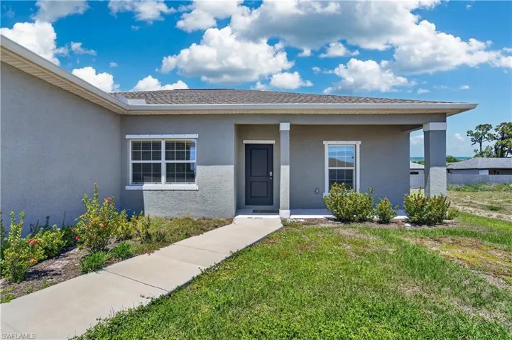 Exterior view of the property featuring a gray facade, a dark entry door, and white-trimmed windows