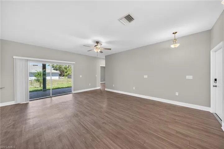 The living area features wood-look flooring, light gray walls, and a ceiling fan