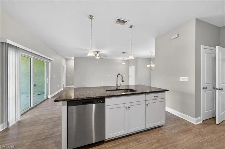 The kitchen features an island with a dark granite countertop, a stainless steel dishwasher, and white cabinetry