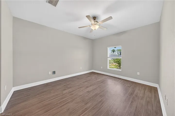 This room features neutral-toned walls, wood-style flooring, and a ceiling fan with an integrated light fixture