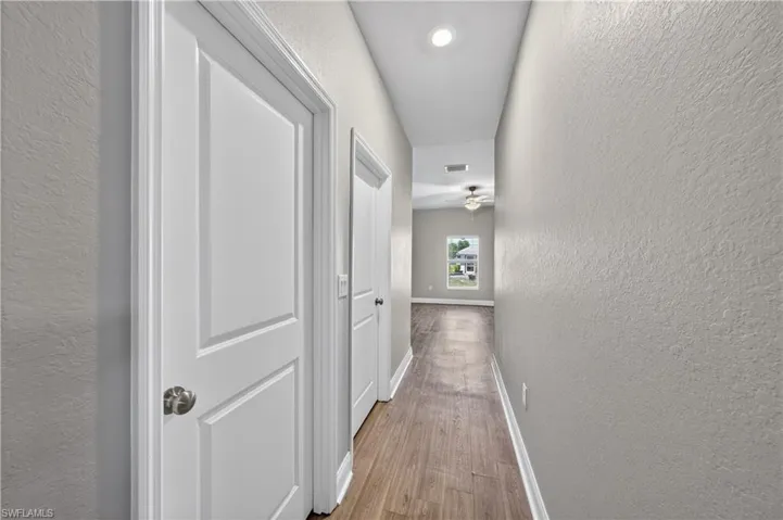 Hallway featuring wood-look flooring, light grey walls, and white paneled doors