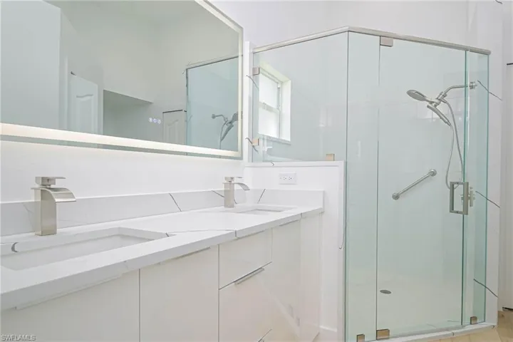 Full bathroom featuring a sink, a shower stall, and double vanity