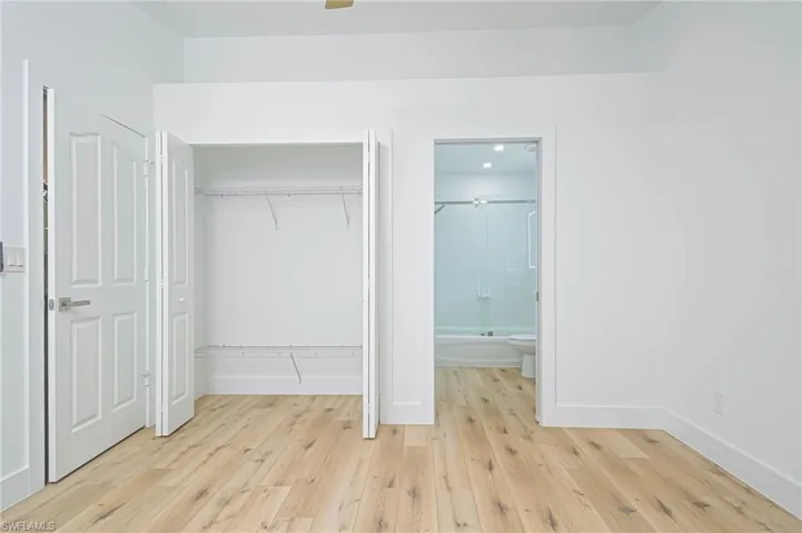 Unfurnished bedroom featuring light wood-style flooring, a closet, baseboards, and connected bathroom