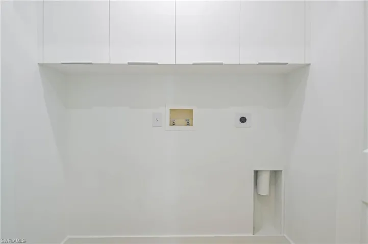Washroom with hookup for an electric dryer, washer hookup, and cabinet space