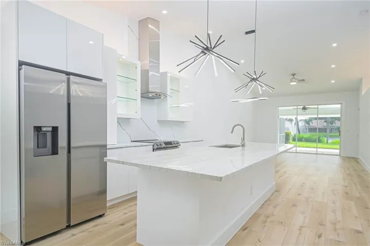Kitchen with modern cabinets, white cabinetry, a kitchen island with sink, a sink, and stainless steel appliances