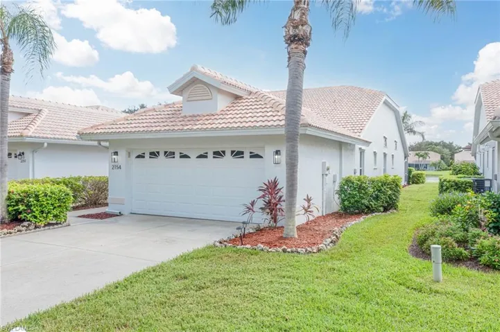 View of home's exterior with a yard, a tile roof, an attached garage, and stucco siding