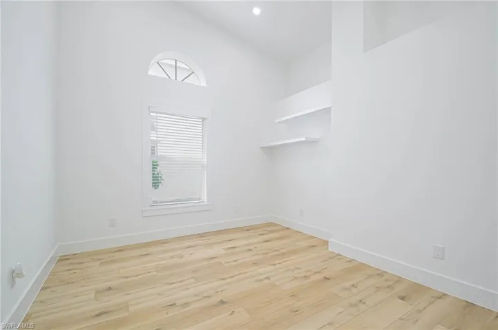 Spare room with baseboards, high vaulted ceiling, and wood finished floors