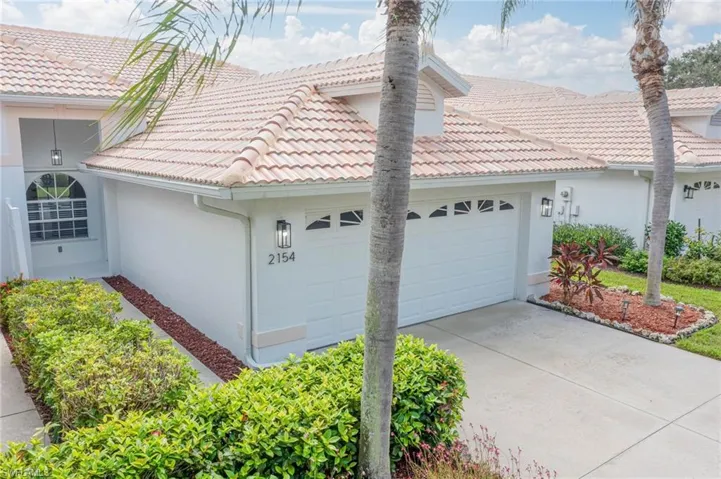 View of side of home with an attached garage, concrete driveway, stucco siding, and a tile roof