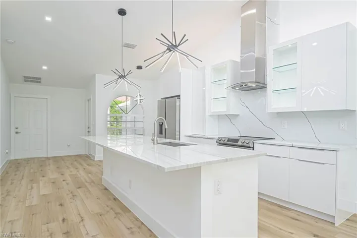 Kitchen featuring visible vents, stainless steel electric stove, wall chimney exhaust hood, and modern cabinets