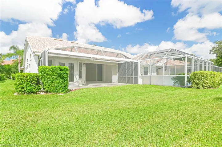 Rear view of property featuring a yard, stucco siding, a patio, and a lanai