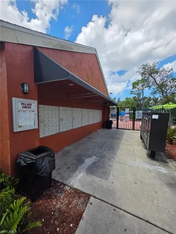 Mailbox station featuring a red stucco exterior, black awning, and multi-unit mailboxes