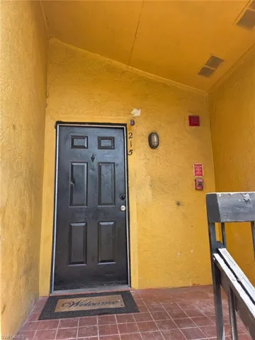 Entryway featuring a black paneled door, terracotta-style floor tiles, and a wall-mounted exterior light fixture