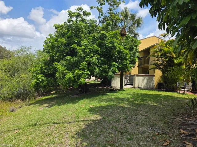 Expansive green lawn featuring mature trees and lush tropical foliage