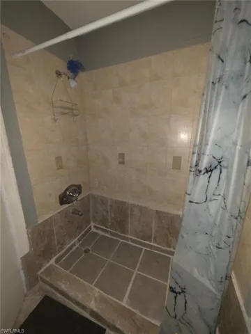 Tiled shower stall featuring light-toned wall tiles, darker base tiles, and a coordinated tiled floor
