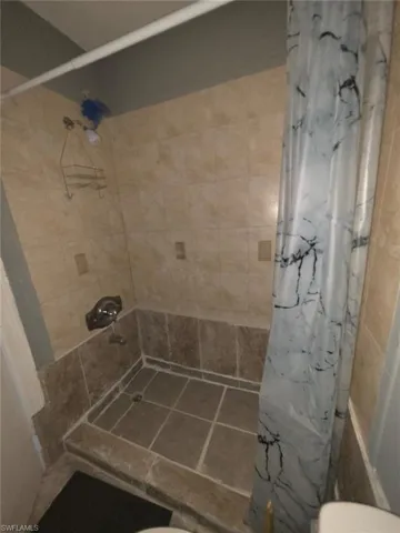 Tiled shower with a metal showerhead and a low threshold entry