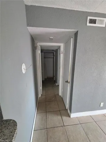 Hallway featuring tile flooring, neutral wall tones, and white trim