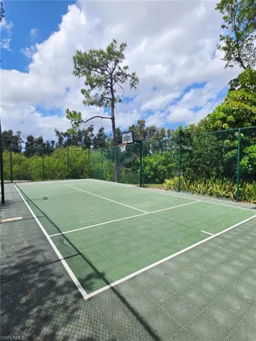 Outdoor sports court featuring a green surface with white line markings, surrounded by a chain-link fence