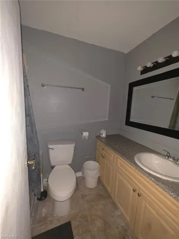 Full bathroom featuring a single vanity with light wood-finish cabinetry, a stone-finish countertop, and an undermount sink