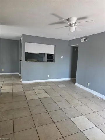 Spacious interior featuring tile flooring, neutral wall tones, and a ceiling fan with integrated lighting