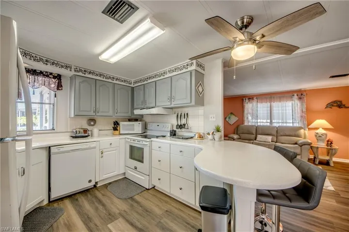 Kitchen featuring a peninsula, white appliances, light wood-style flooring, and visible vents
