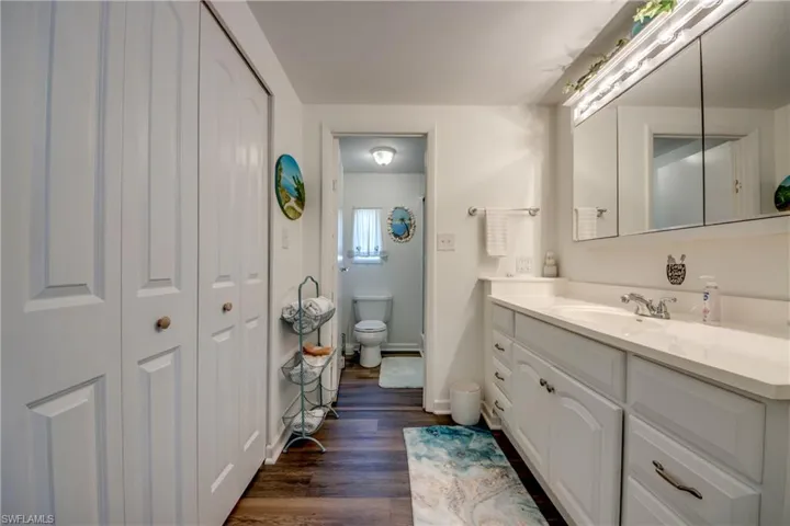 Bathroom with walk in shower, vanity, toilet, baseboards, and wood finished floors