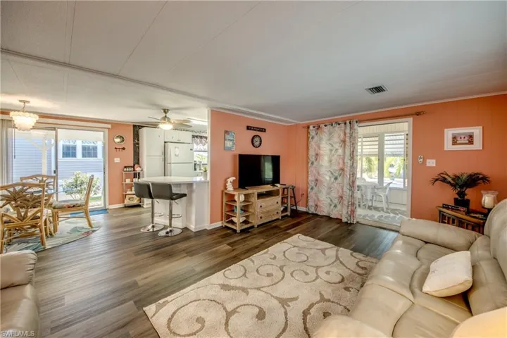 Living room with visible vents, a ceiling fan, and dark wood-style floors