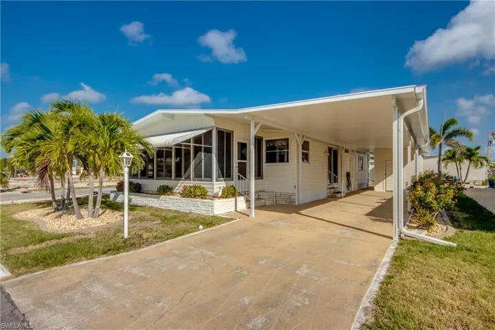 Back of house with concrete driveway, entry steps, a sunroom, and a carport